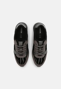 Ett par svarta och grå Geox-sneakers med snörning, detaljer i mocka och läder, samt zebramönster, sedd ovanifrån mot vit bakgrund.