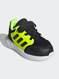 Black athletic shoe with neon green accents and a textured mesh upper. Features a velcro strap and a white outsole for grip.