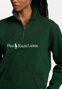 Felpa verde con zip e colletto alto, dotata di tasca frontale e logo ricamato bianco "Polo Ralph Lauren". Tessuto liscio.