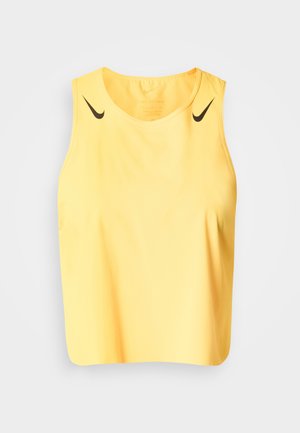 Κίτρινη αθλητική μπλούζα χωρίς μανίκια με στρογγυλή λαιμόκοψη και δύο μικρά μαύρα λογότυπα Nike κοντά στους ώμους σε λευκό φόντο.