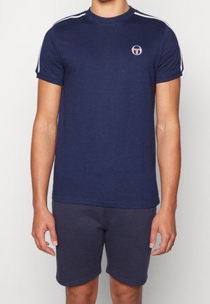 Navy blue cotton t-shirt with short sleeves, white stripes on shoulders, and a small circular logo on the chest. Paired with dark shorts.