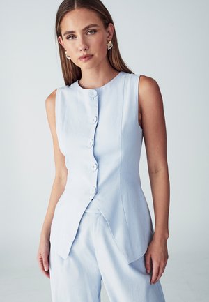 Camicetta senza maniche di colore azzurro chiaro con cinque bottoni, colletto tondo e silhouette aderente con orlo svasato.
