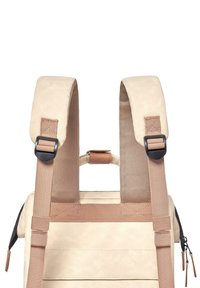 Hellbeige Rucksack mit gepolsterten Schultergurten, verstellbaren braunen Riemen und glatter Textur. Verfügt über elegante Reißverschlusstaschen und dezente Nähte.