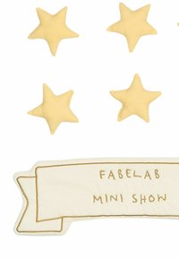 Geltoni audinio žvaigždės su minkšta tekstūra išdėstytos virš kremo spalvos vėliavos, kurioje auksiniais siuvinėjimais parašyta „FABELAB MINI SHOW“.