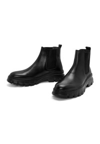 Botas Chelsea de cuero negro con paneles elásticos en los costados y suelas de goma gruesas. Textura suave y tiradores para ponerlas y quitarlas con facilidad.