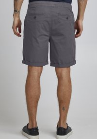 Grå bomullsshorts med rullekanter, to baklommer og snorjustering i livet, med en glatt tekstur og en uformell design.