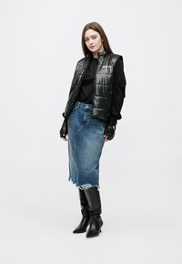 Juoda paminkštinta liemenė dėvima ant juodos ilgomis rankovėmis palaidinės, derinama su mėlyna džinsine suknele ir juodais žieminiais batais iki kelių. Faktūra: blizgi liemenė, pablukęs suknelės kraštas.