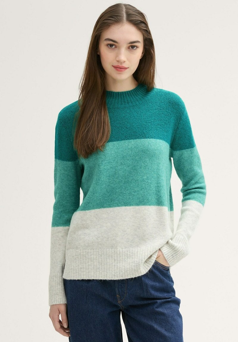 Tropfengrüner und grauer gestreifter Pullover aus weichem Strickstoff. Mit Rundhalsausschnitt und gerippten Bündchen. Lässige Passform mit seitlichen Schlitzen.