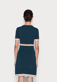 Vestido de punto azul marino con mangas cortas, acentos a rayas en blanco y marrón en las mangas y el dobladillo, con una silueta ajustada.