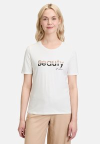 Hvid kortærmet bomuldstrøje med "Beauty" i sort og mønstret skrift, med "of nature" i en flydende skrift nedenfor.