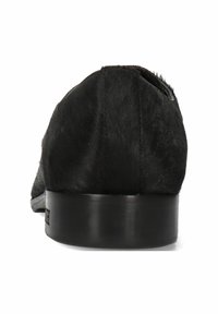 Svart slip-on sko med en texturerad päsliknande ovandel, rund tå och en slät svart häl. Har subtil branding på sidan.