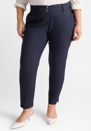Pantaloni blu navy con una vestibilità sartoriale, caratterizzati da un alto punto vita, chiusura a doppio bottone e lievi spacchi laterali alle caviglie. Tessuto morbido.