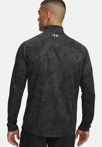 Langarmpige sportshirt in het zwart met een gestructureerd camouflagedesign, hoge kraag en een slanke pasvorm. Gemaakt van vochtregulerend materiaal.