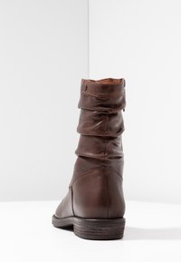 Brun läderankelstövel med rynkad design, rund tå, låg klack med staplad effekt och diskreta sömdetaljer. Slät baktill och på sidorna.