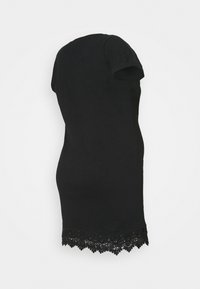 Robe t-shirt noire à manches courtes, avec un ourlet en dentelle texturée, présentant des motifs floraux complexes en bas.