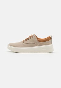 Zapatillas de lona beige con detalles de ante marrón, puntera redonda y suela de goma blanca. Cuenta con cordones marrones y un tirador en el talón para facilitar su uso.
