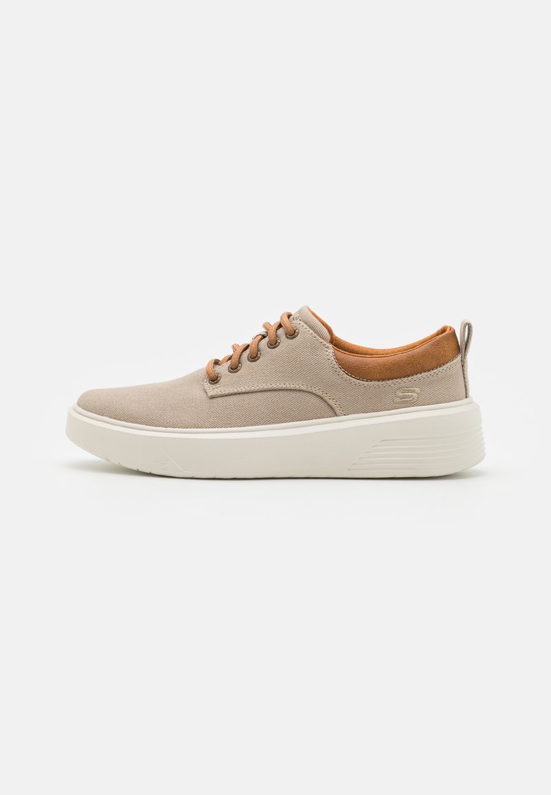 Zapatillas de lona beige con detalles de ante marrón, puntera redonda y suela de goma blanca. Cuenta con cordones marrones y un tirador en el talón para facilitar su uso.