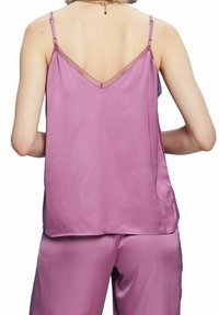 Lila satasolär med tunna axelband och en texturerad V-halsringning. Det släta tyget faller mjukt och kompletterar matchande satinsbyxor.