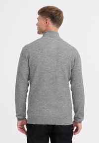 Szary sweter z wysokim kołnierzem wykonany z miękkiego materiału. Posiada długie rękawy, prążkowane mankiety i lekko teksturowane wykończenie.