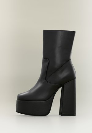 Bottine noire à plateforme avec talon bloc haut et finition en cuir lisse sur fond neutre.