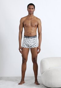 Bokserinės trumpikės su juodos ir baltos spalvos geometriniu raštu, minkšta medžiaga, elastinė juosmens juosta su "KARL LAGERFELD" logotipu ir aptempta forma.