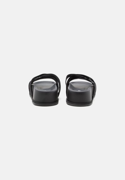 Paire de sandales slides noires à bout ouvert avec petits talons blocs, vues de dos sur un fond clair uni.