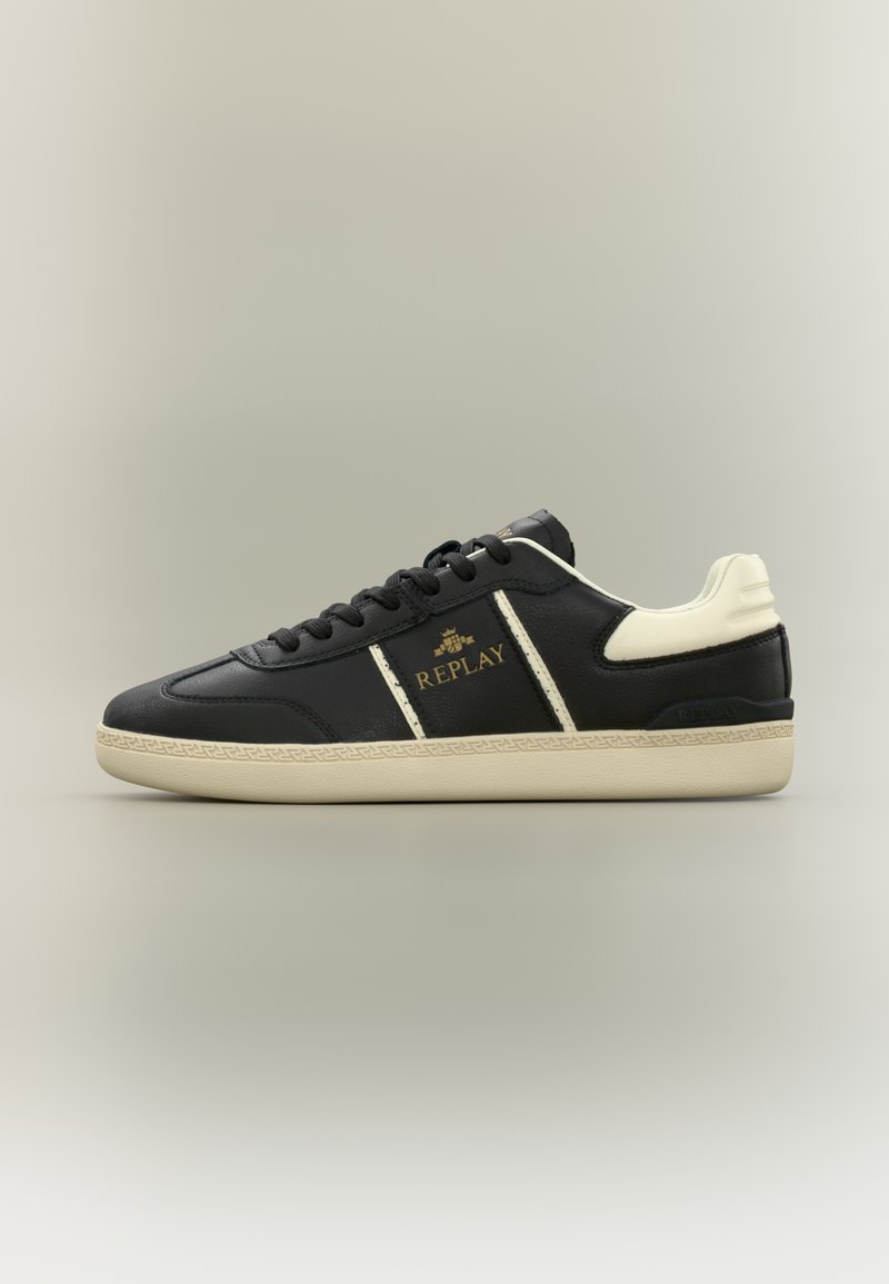 Baskets noires avec des accents crème, dessus en cuir texturé, bout arrondi et lacets plats. Présente un logo détaillé sur le côté et le talon.