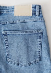 Jeans in denim azzurro chiaro con una sola tasca posteriore. La cintura presenta una patch in pelle beige con la scritta "OPUS." Design classico e testurizzato.