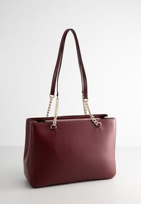 Sac à main rectangulaire en cuir bordeaux avec double chaîne dorée et bretelles en cuir, design structuré et texture lisse.