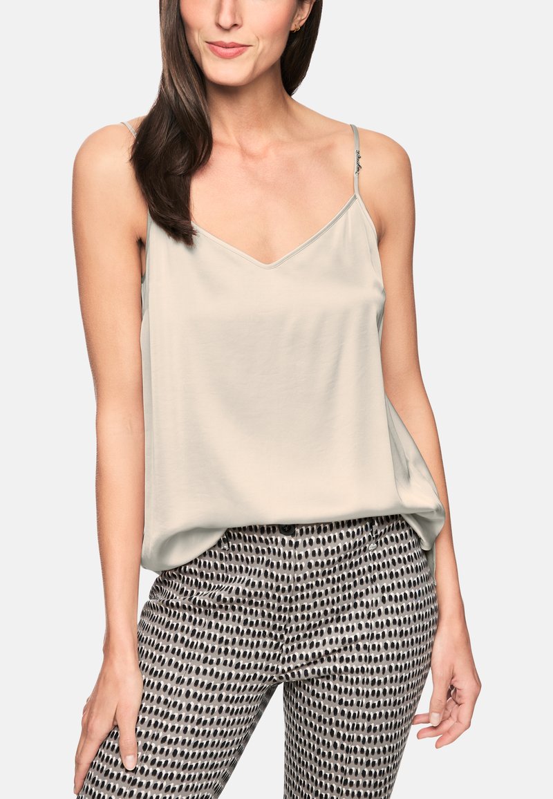 Light gray camisole with a V-neck and thin straps, paired with high-waisted trousers featuring a dark polka dot pattern on a light background.