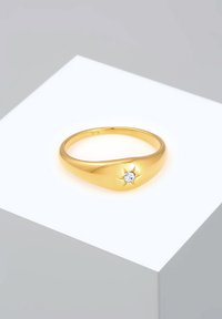 Anello d'oro con un design liscio e curvo e un accento a forma di stella con una pietra trasparente al centro. Finitura lucida, semplicità ed eleganza.