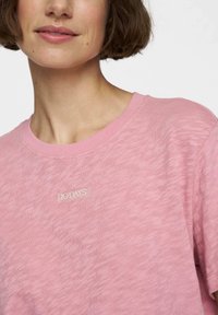 Lyserød T-shirt lavet af blødt stof, med rund halsudskæring og et lille "10 DAYS" logo mærke syet på forsiden.