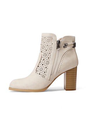 Stivale alla caviglia beige con design floreale perforato, zip laterale e tacco in legno impilato. Materiale in pelle liscia con punta arrotondata.