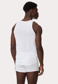 Weißes geripptes Tanktop mit figurbetontem Design und Rundhalsausschnitt, kombiniert mit weißen Boxershorts, auf einem männlichen Model von hinten präsentiert.