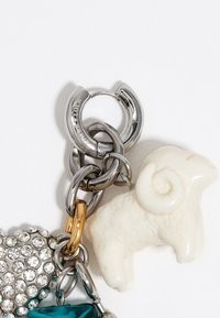 Breloczek do kluczy z lekkim metalowym łącznikiem w kolorze srebrnym, białą ceramiczną baraniną, turkusowym kamieniem szlachetnym oraz sercem wysadzanym kryształkami.