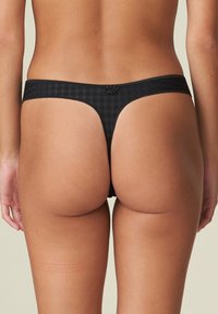 Zwarte geblokte string met een gladde textuur en een smalle band. Voorzien van een decoratieve bloemdetail aan de achterkant.