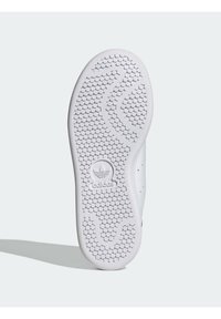 Suola di scarpa Adidas bianca con motivo di battistrada circolare e logo Adidas al centro, fotografata su uno sfondo grigio chiaro.