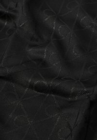 Fekete szövet, finom, fényes mintával, összefonódó hurkokkal. Sima tapintású, könnyű és finoman omlik.