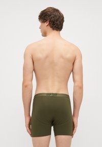 Boxeri de culoare verde măsliniu, dintr-un material moale, cu un elastic pe talie ce prezintă branding-ul repetat "GAP". Textură netedă și ajustare confortabilă.