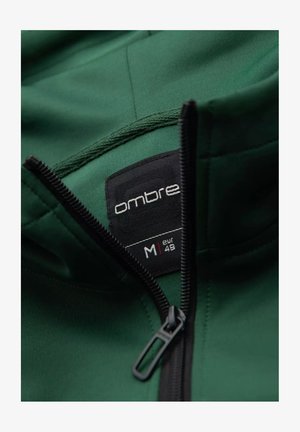 Zielona bluza z kapturem z czarną etykietą z napisem "ombre" oraz rozmiarem "M" (EUR 48). Posiada zamek błyskawiczny oraz gładki, teksturowany materiał.
