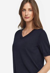 Marinblå V-ringad t-shirt i mjukt tyg med korta ärmar och avslappnad passform, som visar en enkel design och sömlös struktur.