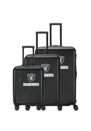 Drei schwarze Hartschalenkoffer mit ausgezogenen Griffen, jeweils mit dem Raiders-Logo und weißem Text "RAIDERS" auf der Vorderseite.