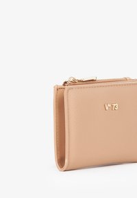 Portafoglio in pelle beige con finitura testurizzata, dotato di una cerniera dorata e dettaglio con logo. Forma compatta e rettangolare.