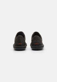 Mustad must suhkruga kingad madala profiiliga ja kummist tald. Omab väikest punast "Camper" logo kontsapooles. Lihtne, voolujooneline disain.