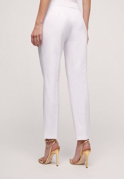 White tailored trousers with a straight cut, featuring a smooth texture and a mid-rise waist. Paired with gold high-heeled sandals.