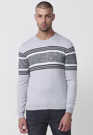 Suéter de pullover gris con un patrón a rayas que presenta líneas horizontales negras y blancas en el pecho y las mangas. Cuello redondo, puños acanalados.