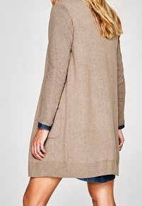 Lys brun cardigan med ribbet struktur, åben front, lange ærmer og sidelommer. Designet for komfort med en afslappet pasform.