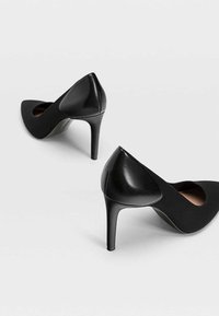 Tacones negros altos con punta afilada y acabado liso y suave. El material superior parece mate, mientras que el tacón tiene un acento brillante.