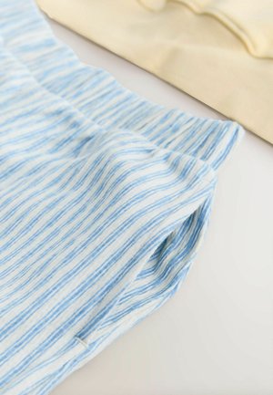 Modro-bíle pruhovaná látka s měkkou texturou; viditelný složený lem, v pozadí doplněná jednoduchým béžovým materiálem.
