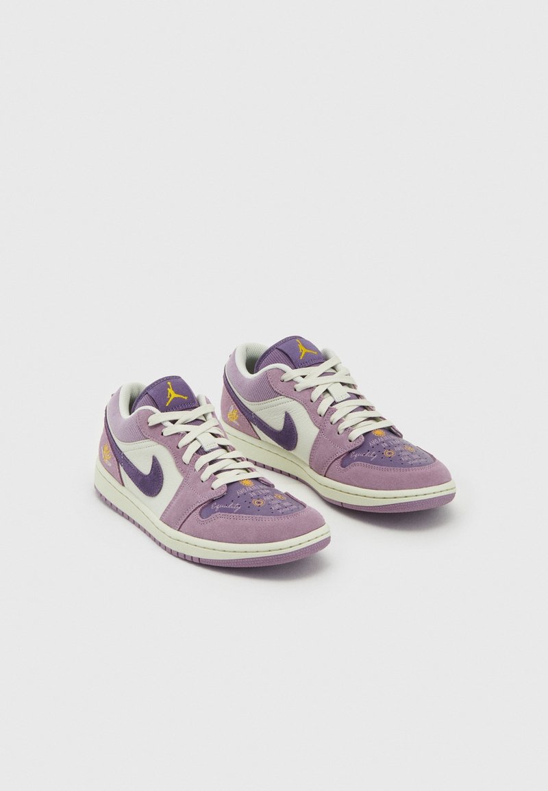Paire de baskets basses violettes et blanches avec lacets blancs, logo Nike violet, accents jaunes et broderie florale sur la pointe.